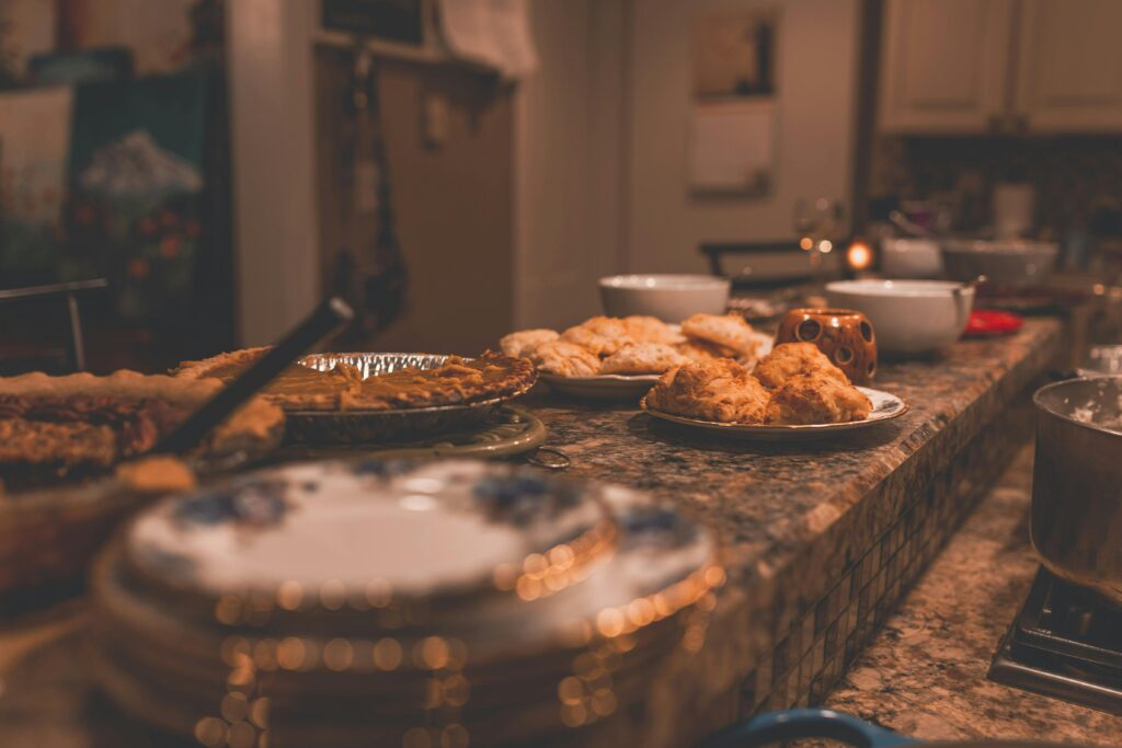Warm and inviting Thanksgiving dinner setup featuring pies and biscuits on a kitchen counter.